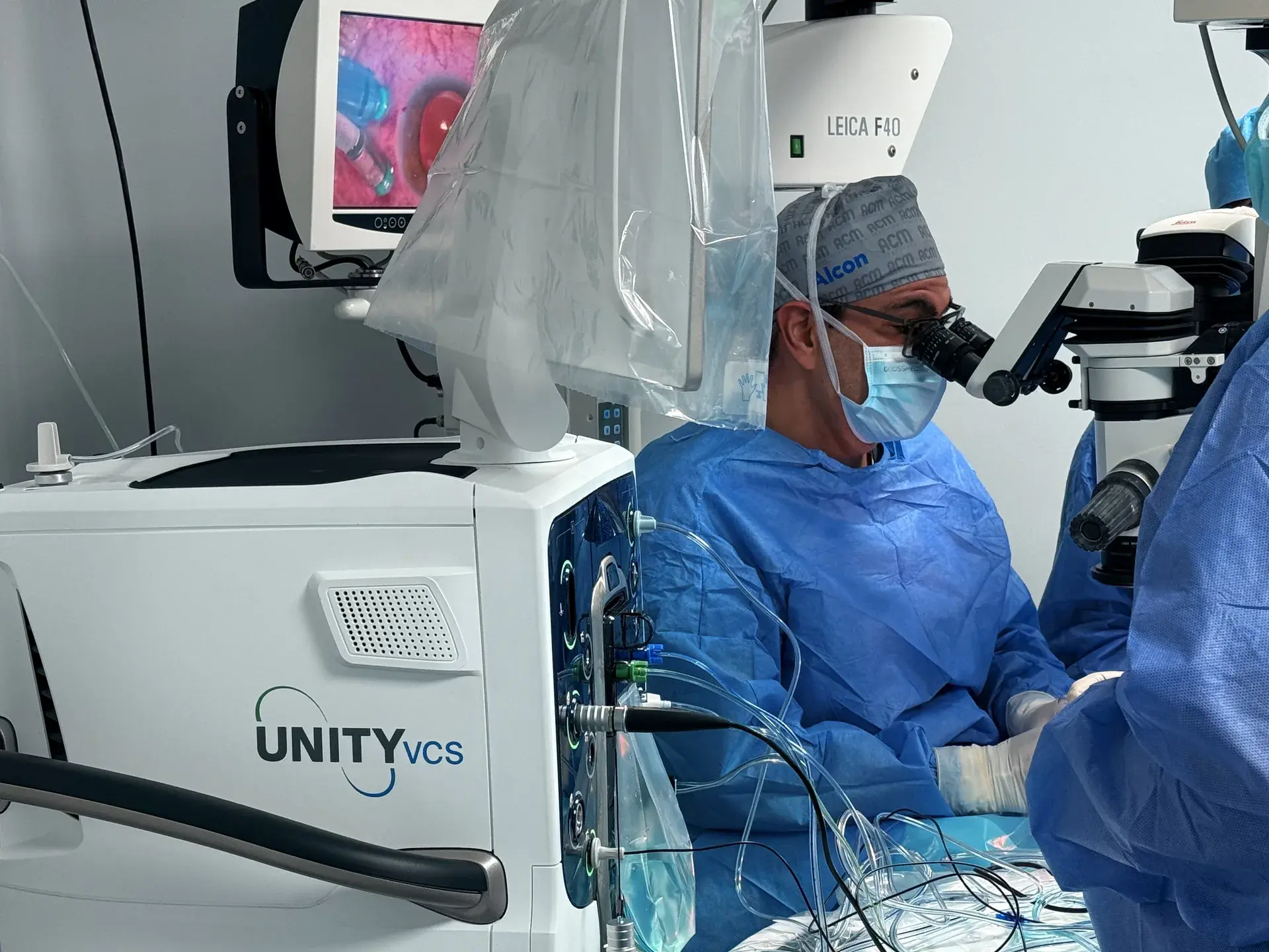 Cirujano operando con el microscopio junto a la consola UNITY VCS